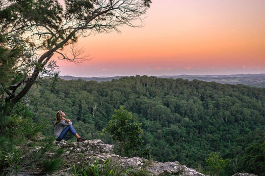 Woman sitting down on a hike watching the sunset